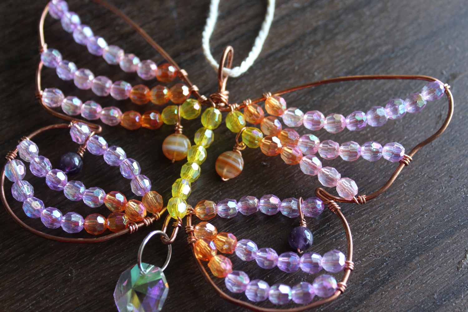 Dragonfly outline with clear prism beads and a square dangle bead at the bottom.